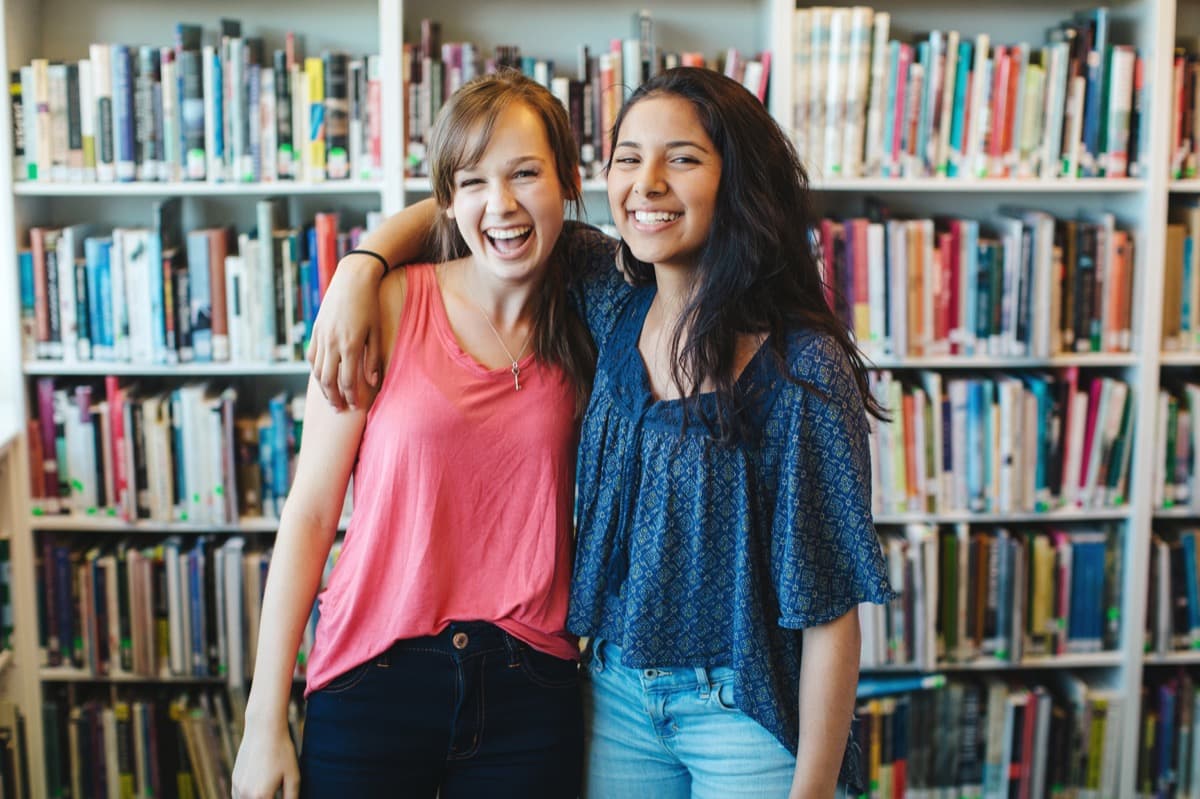 Two students laughing together in a library
