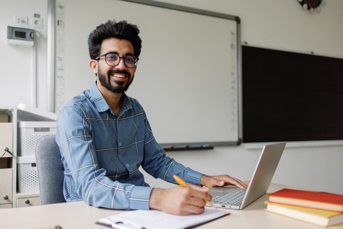 An educator working at a laptop in a classroom
