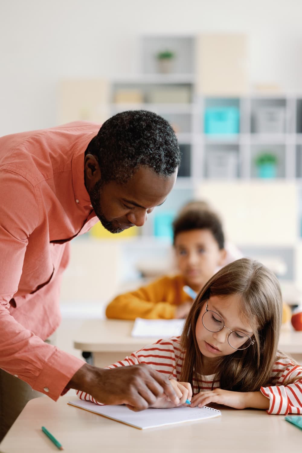 A teacher helping a student at a classroom desk