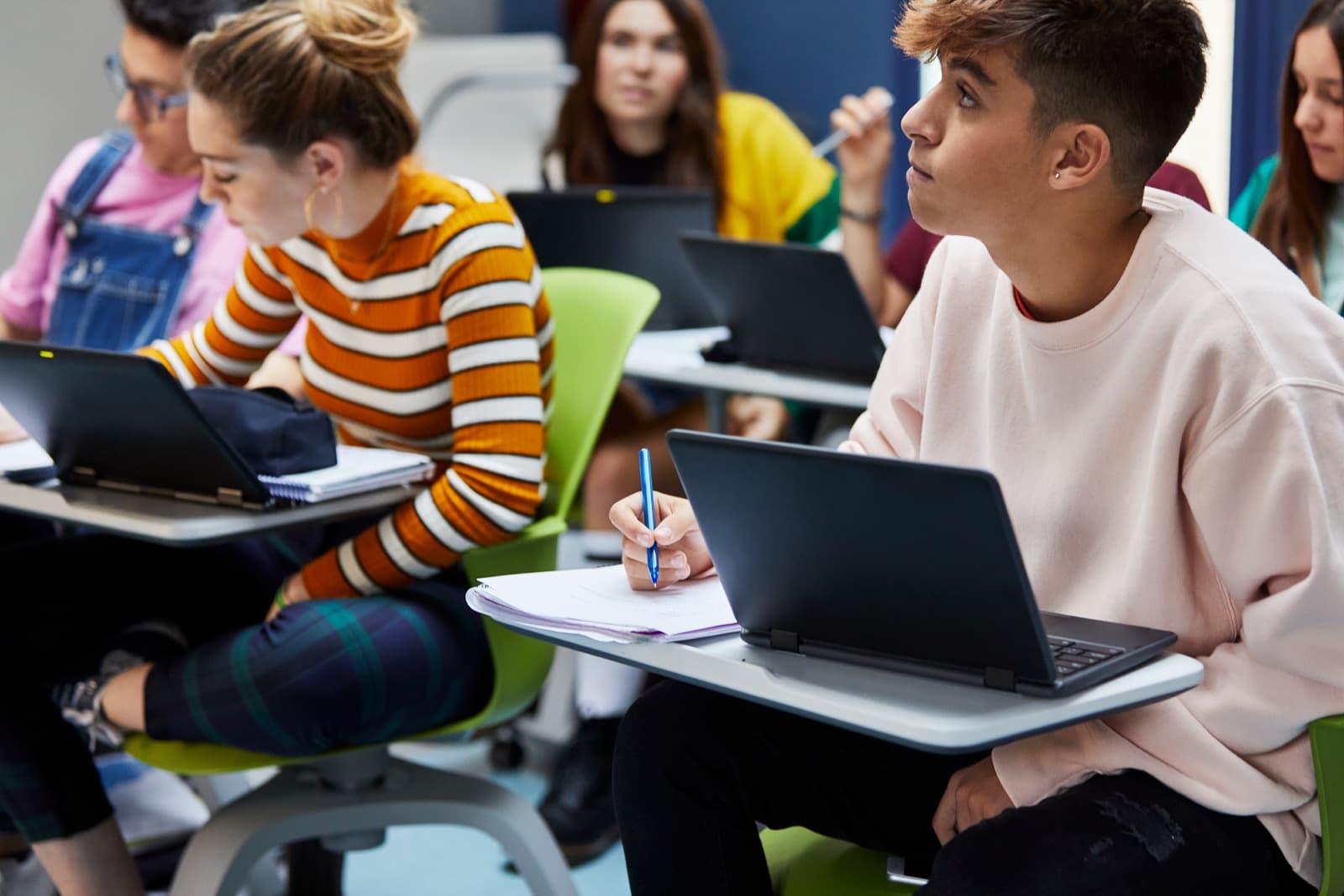 Teens working on laptops together in a classroom