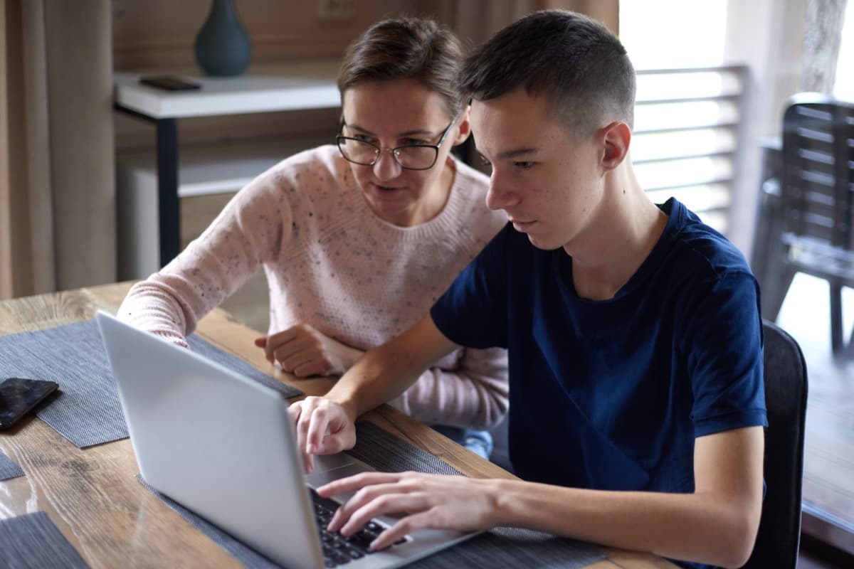 An adult helping a student work through an idea at a laptop