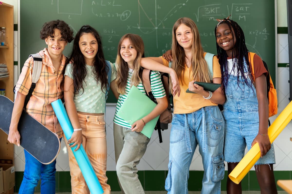A group of middle-school students smiling together in a classroom